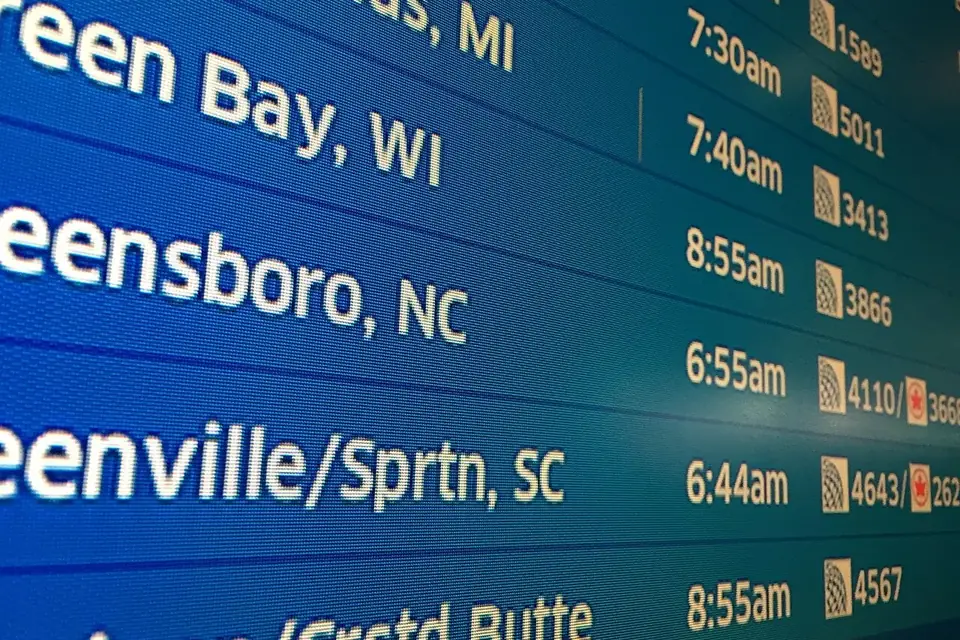 Close-up of an airport departures board listing destinations, departure times and flight numbers