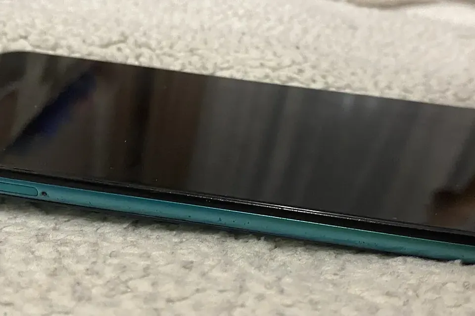 A smartphone with a dark screen lying flat on a pale woolly blanket